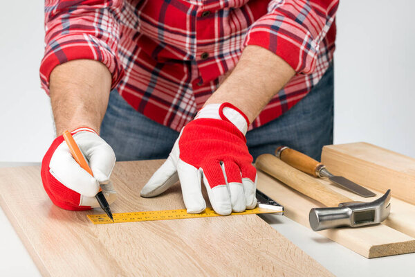 Adult carpenter or craftsman with a pencil and the carpenter's square draw a line on board. Manifacturing of furniture at home. Do it Yourself concept