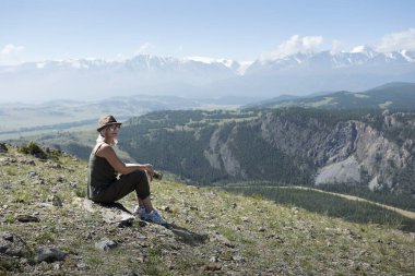 Dağın tepesinde oturan ve vadinin tadını çıkaran kadın. Dağlarda Yürüyüş Kavramı.