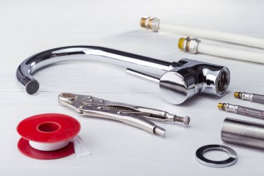 Musluk, tesisatçı aletleri ve ekipmanlar banyoda. Tesisat malzemeleri beyaz başlık üzerine.