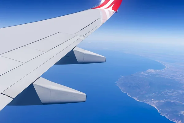 Airplane wing fly over sea and coast. Travel vacation concept.