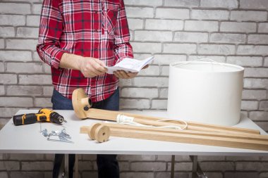 Adam okuma talimatı veriyor. Lambayı lambanın yanına kurun. DIY kavramı.