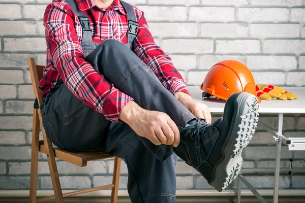 Worker putting on working boots at the locker room in a factory. Safety construction concept.