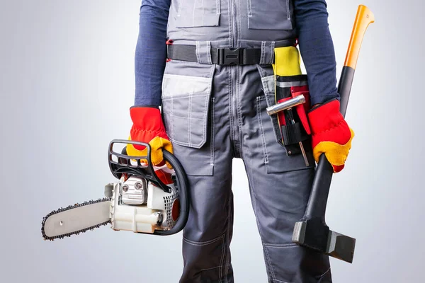Gri arka plan yakınlarında elektrikli testere ve baltalı oduncu..