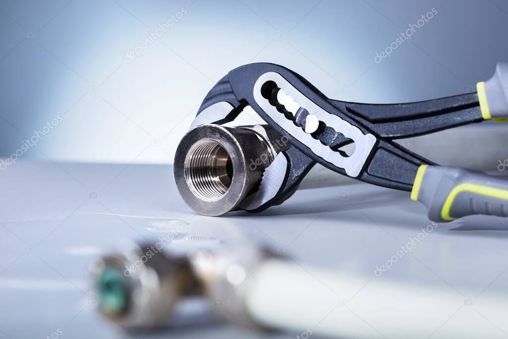  Water supply tube and adjustable wrench on grey background. Plumbing repair service concept.
