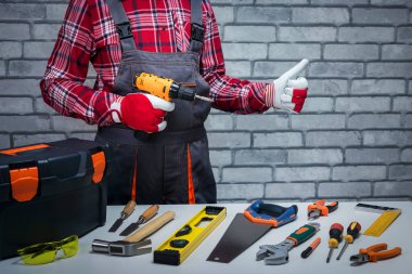 Tamirci işe hazır. Farklı aletleri olan bir tamirci baş parmağını kaldırıyor. Onarım kavramı.