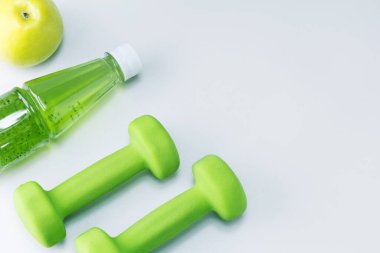 Dambıllar, taze meyve elması ve açık gri yüzeyde fotokopi alanı olan multivitamin suyu. Sağlıklı spor ve diyet kavramı.