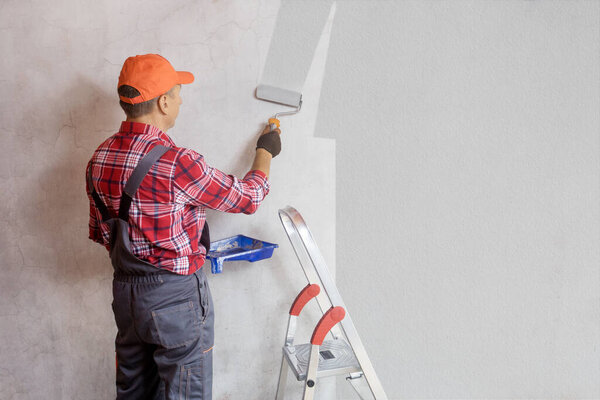 Painter painting a wall with paint roller. Home decoration, repair concept