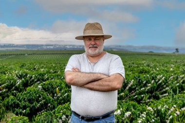 Brezilya 'da, çiçekli kahve tarlası geçmişi olan orta yaşlı çiftçinin portresi.