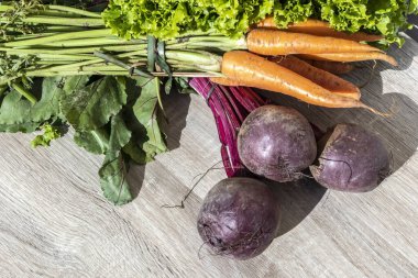 Brezilya 'daki tahta masada taze organik havuç, pancar ve marul yaprakları.