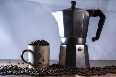 Kahve fincanında kahve çekirdekleri ve Brezilya 'da tahta bir masada İtalyan kahve makinası.