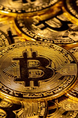 Sarı arka planda altın Bitcoin paraların yakın plan görüntüsü.