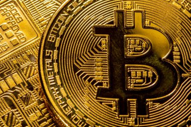 Sarı arka planda altın Bitcoin paraların yakın plan görüntüsü.