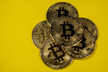 Sarı arka planda altın Bitcoin paraların yakın plan görüntüsü.
