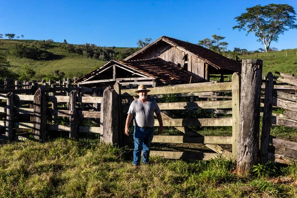 middle-aged farmer and cattle rancher observes an old corral to place the animals