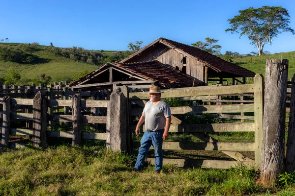 middle-aged farmer and cattle rancher observes an old corral to place the animals