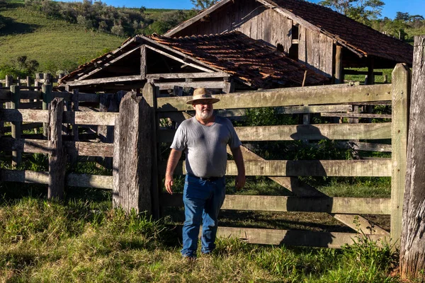 middle-aged farmer and cattle rancher observes an old corral to place the animals