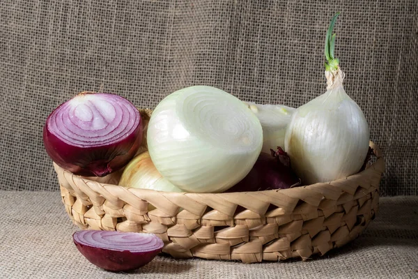 Zwiebeln Verschiedener Sorten Einem Strohkorb Auf Einem Holztisch Mit Jute — Stockfoto