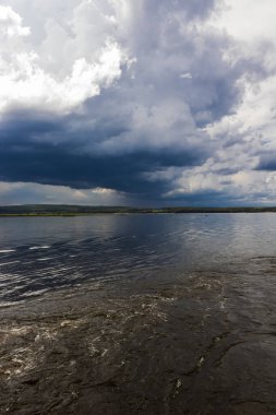 Brezilya, Paranapanema Nehri 'nde dramatik bir birliktelik. Farklı renklerdeki sular, güçlü fırtınalı bir gökyüzünün altında birleşerek doğanın zıtlığını ve gücünü gösterir..