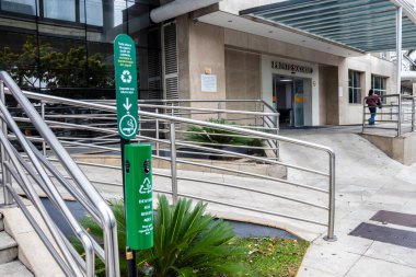Sao Paulo, SP, Brazil, Dec 17, 2025. A green cigarette butt recycling bin at the entrance to the Salvalus Hospital emergency room. The sign explains that the waste is transformed into paper.