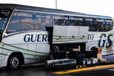 Marilia, SP, Brezilya, 26 Eylül 2025. Marilia terminalinde bir otobüs, bagaj bölümü açık, bölgesel ulaşım ve teslimat hizmetleri için kargo ve paketleri yükleniyor..