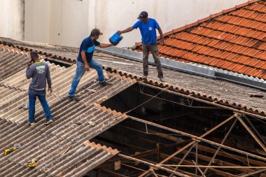 Marilia, Sao Paulo, Brezilya, 14 Ekim 2025. Marilia 'nın merkezindeki ticari bir noktanın çatısını yenilemek için bir eve metal çarşaf döşeyen bir işçinin üst görüntüsü.