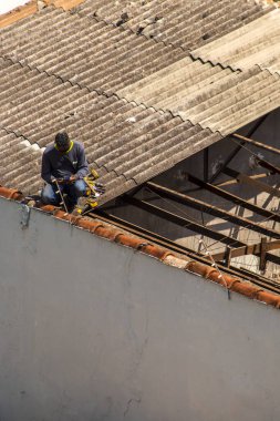 Marilia, Sao Paulo, Brezilya, 14 Ekim 2025. Marilia 'nın merkezindeki ticari bir noktanın çatısını yenilemek için bir eve metal çarşaf döşeyen bir işçinin üst görüntüsü.