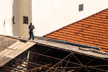 Marilia, Sao Paulo, Brezilya, 14 Ekim 2025. Marilia 'nın merkezindeki ticari bir noktanın çatısını yenilemek için bir eve metal çarşaf döşeyen bir işçinin üst görüntüsü.