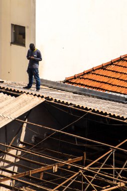 Marilia, Sao Paulo, Brezilya, 14 Ekim 2025. Marilia 'nın merkezindeki ticari bir noktanın çatısını yenilemek için bir eve metal çarşaf döşeyen bir işçinin üst görüntüsü.