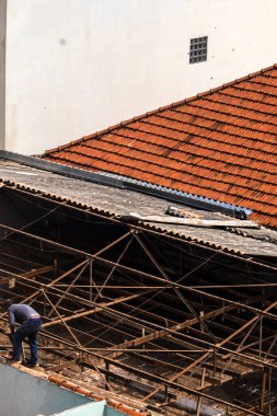 Marilia, Sao Paulo, Brezilya, 14 Ekim 2025. Marilia 'nın merkezindeki ticari bir noktanın çatısını yenilemek için bir eve metal çarşaf döşeyen bir işçinin üst görüntüsü.