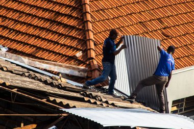 Marilia, Sao Paulo, Brezilya, 14 Ekim 2025. Marilia 'nın merkezindeki ticari bir noktanın çatısını yenilemek için bir eve metal çarşaf döşeyen bir işçinin üst görüntüsü.