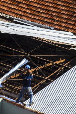 Marilia, Sao Paulo, Brezilya, 14 Ekim 2025. Marilia 'nın merkezindeki ticari bir noktanın çatısını yenilemek için bir eve metal çarşaf döşeyen bir işçinin üst görüntüsü.