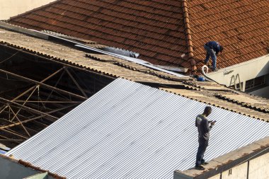 Marilia, Sao Paulo, Brezilya, 14 Ekim 2025. Marilia 'nın merkezindeki ticari bir noktanın çatısını yenilemek için bir eve metal çarşaf döşeyen bir işçinin üst görüntüsü.