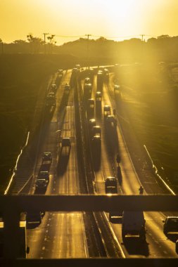 Marilia, SP, Brezilya, 19 Kasım 2025. Marilia 'da gün batımında SP-294 otoyolu. Araç ve kamyonların yoğun trafiği, altın saat ışığıyla aydınlatılan yeşil arazide akıyor..