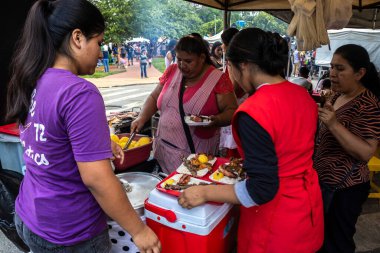 Sao Paulo, Brezilya, 12 / 21 / 2025. Sao Paulo 'da Bolivya' da bir markette canlı bir sahne. Kadınlar, zengin kültür ve aşçılık geleneklerini sergileyerek geleneksel antiko ve diğer etleri ızgara yapıyorlar.