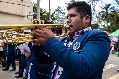 Sao Paulo, Brezilya, 12 / 21 / 2025. Bando, Kantuta Meydanı 'nda konser veriyor. Mavi üniformalı müzisyenler, bir Bolivya sokak fuarı sırasında zengin kültürel çeşitliliği yansıtan rüzgar enstrümanları çalıyorlar.