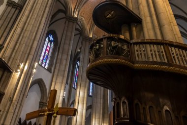 Sao Paulo, Brezilya, 12 / 21 / 2025. Brezilya 'daki tarihi neo-gotik Sao Paulo Katedrali' nin içinde, süslü ahşap kürsü, devasa taş sütunlar ve vitray pencereler üzerinde duruluyor.