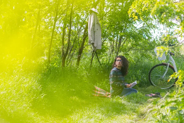 Krásná mladá brunetka žena, čtení knihy v parku — Stock fotografie