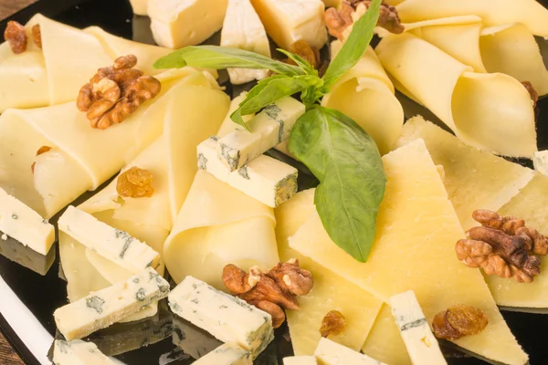 Different types of cheese, on a black plate — Stock Photo, Image