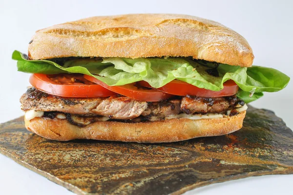 Tasty pork steak sandwich in a ciabatta with tomatos, lettuce — Stock Photo, Image