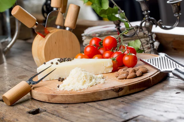 Grated pecorino cheese on wooden cutting board with tomatoes, selective focus — Stock Photo, Image