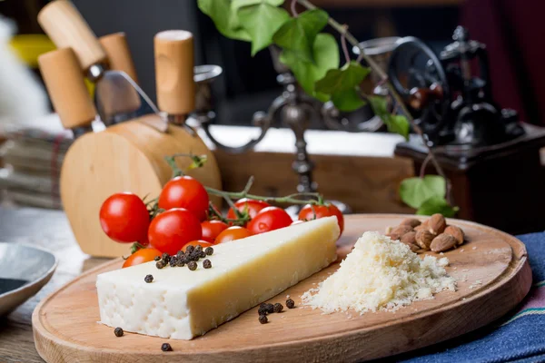 Grated pecorino cheese on wooden cutting board with tomatoes, selective focus — Stock Photo, Image