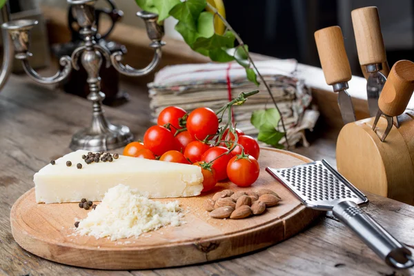 Grated pecorino cheese on wooden cutting board with tomatoes, selective focus — Stock Photo, Image