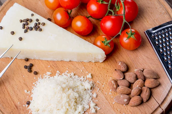 Grated pecorino cheese on wooden cutting board with tomatoes, selective focus — Stock Photo, Image