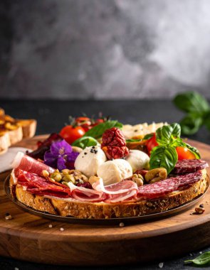 Tahta bir çeşit et, peynir ve taze sebzeler barındırır. Sahne, sıcak ışıklarla dolu bir mutfakta geçiyor. Bu düzenleme bir yemek sırasında paylaşım ve keyif davet eder.