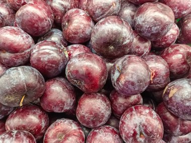 Çerçeveyi yoğun, taze toplanmış koyu kırmızı ve mor eriklerle dolduran bir makro yakın çekim. Meyve, doğal tozlu çiçeklenmesini ve ince renk değişimlerini gösteriyor. Sağlıkla ilgili kavramlar için ideal, zengin bir besin dokusu ve desen oluşturuyor.