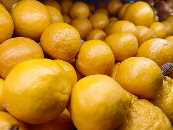 Çerçeveyi dolduran yoğun ve renkli taze toplanmış parlak turuncu portakal (mandalina) yığınını yakına çeken bir makro çekim. Resim, meyvenin parlak dokusunu ve bolluğunu vurgular, narenciye ve sağlıkla ilgili konular için idealdir.