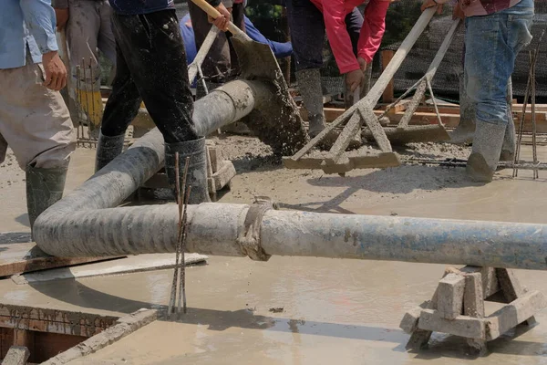 İnşaat işçilerini büyük bir boru ve pompayla bir inşaat sahasının zeminine ıslak, sıvı beton dökerek yakalamak.