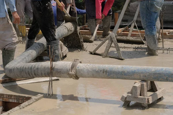 İnşaat işçilerini büyük bir boru ve pompayla bir inşaat sahasının zeminine ıslak, sıvı beton dökerek yakalamak.