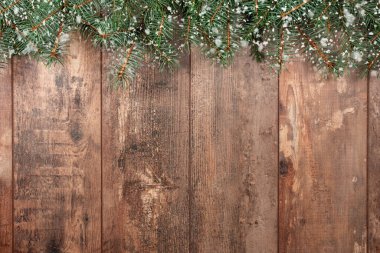 Noel arkaplanı. Köknar dalları ve kar taneleri olan eski bir ahşap arka plan. Tebrik mesajı için yer var. Noel kartı. Üst Manzara. Kar tanelerinin etkisi.