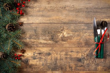 Yılbaşı şenlikli Noel yemeği konsepti. Karanlık bir kırsal masada Noel süsleri ve çatal bıçak takımı. Noel sofrası kurulumu. Kış tatili geçmişi. Üst görünüm, düz görünüm, kopyalama alanı